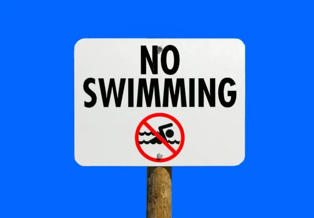 An illustrative no-swimming sign against a blue background