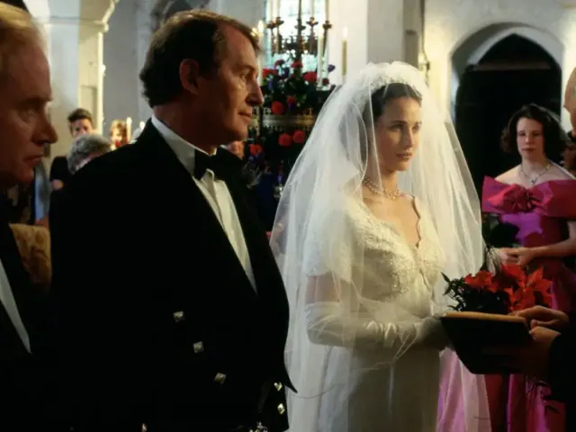 Andie MacDowell as Carrie wearing a long-sleeved lace wedding dress and veil
