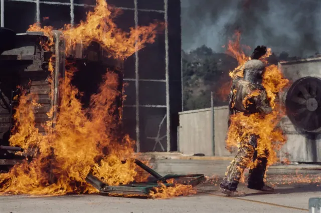 Archive sequence of Kitty O'Neil performing a stunt involving a burning vehicle.