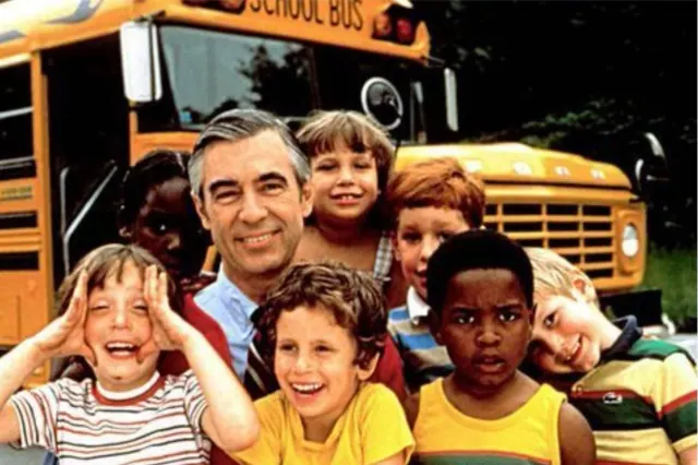 Fred Rogers with children in front of a yellow school bus