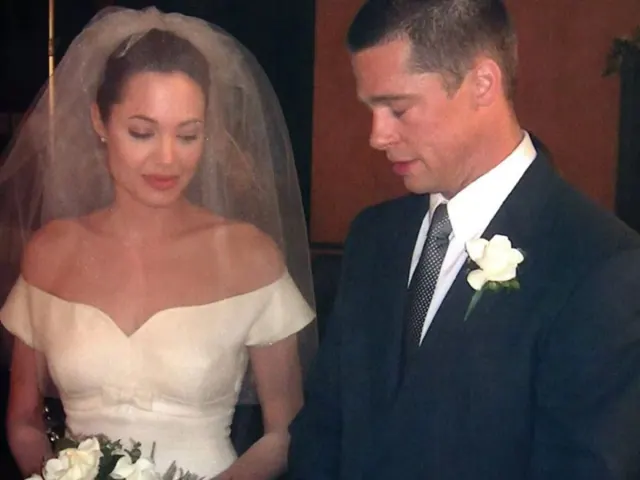 Angelina Jolie as Jane wearing a short off-the-shoulder bridal dress beside Brad Pitt