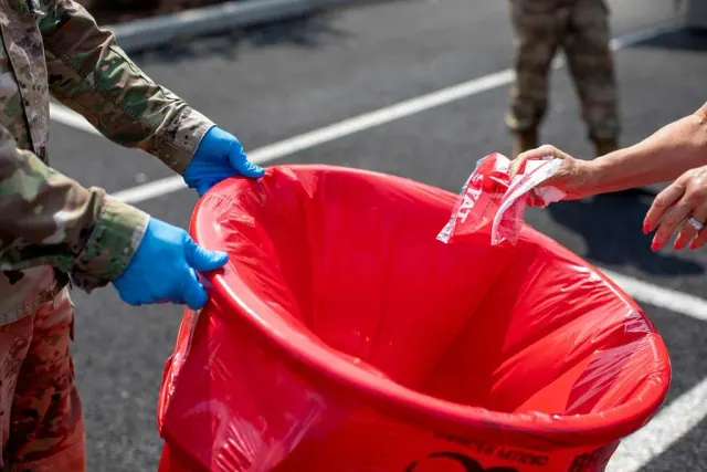 A uniformed person holding a red waste bag, used as an illustration
