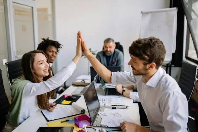 People exchanging a high five at a meeting, used as an illustration