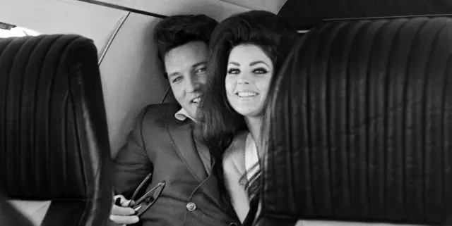 Priscilla and Elvis seated beside each other in an aircraft