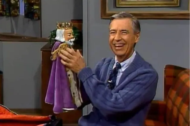 Fred Rogers holding a crowned puppet on the Neighborhood set