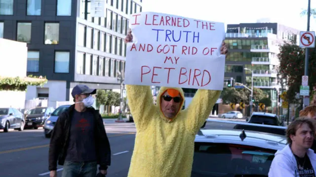 Protester holding a sign claiming a pet bird died after the truth was discovered