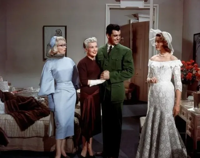 Lauren Bacall as Schatze wearing a lace bridal gown and broad white hat