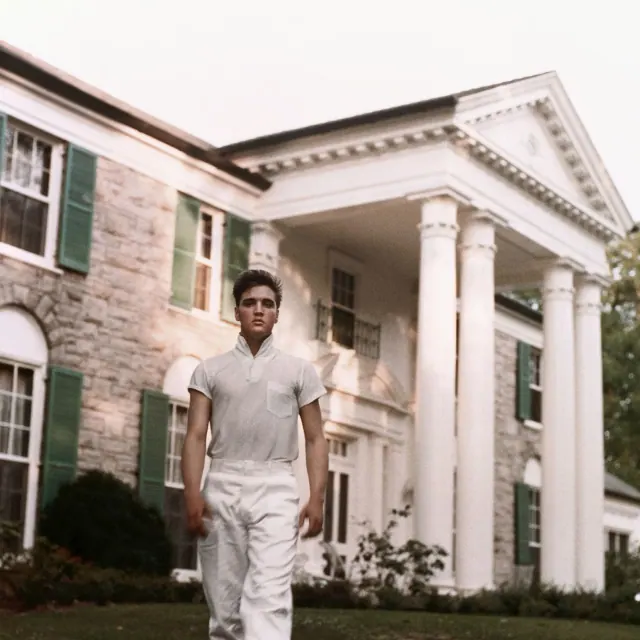 Elvis standing outside Graceland's columned entrance