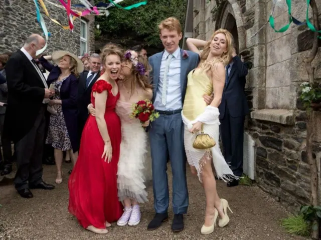 Rachel McAdams as Mary wearing a red wedding dress beside Domhnall Gleeson as Tim and guests