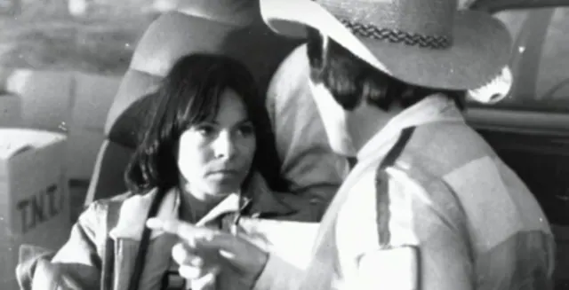 Kitty O'Neil seated in a vehicle speaking with another person.