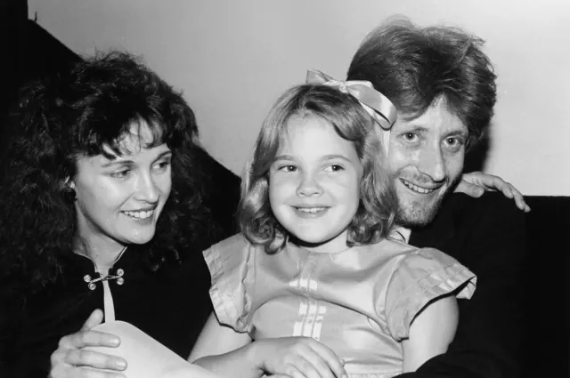 Young Drew Barrymore between two adults in a black-and-white archive photograph