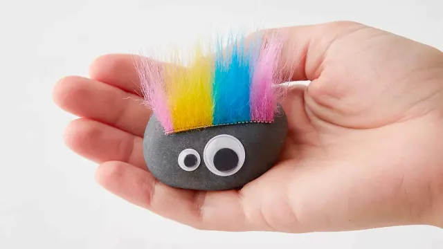 Novelty rock with rainbow-colored hair held in a palm