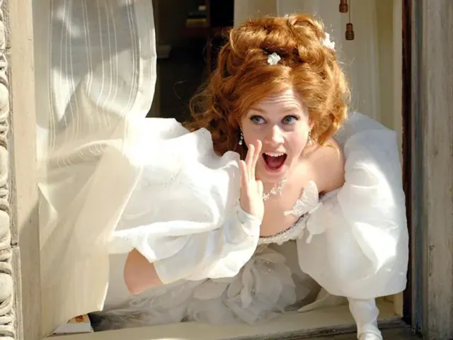 Amy Adams as Giselle raising her arms in a wedding gown with very large puffed sleeves