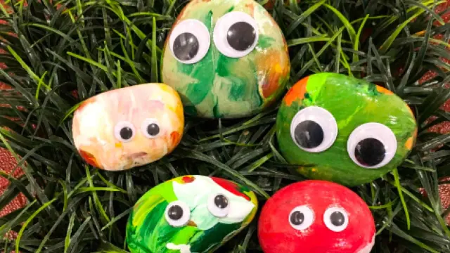 Painted craft rocks with faces and spots on grass