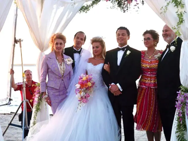 Margot Robbie as Naomi in a full wedding gown beside Leonardo DiCaprio as Jordan