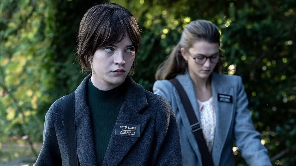 Sister Barnes (Sophie Thatcher) and Sister Paxton (Chloe East) standing in front of greenery in