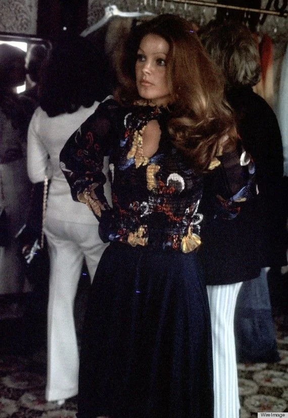 Priscilla in a dark outfit with a floral upper section