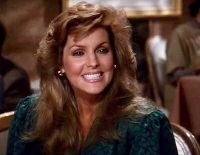 Priscilla Presley with brown hair in a high-necked outfit