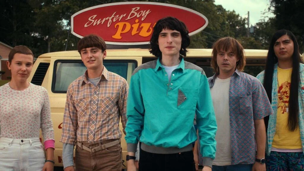 Eleven, Will, Mike, and Jonathan standing in front of a pizza van in "Stranger Things"