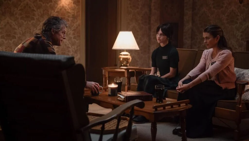 Mr. Reed (Hugh Grant) talking to Sister Barnes (Sophie Thatcher) and Sister Paxton (Chloe East) in his living room.
