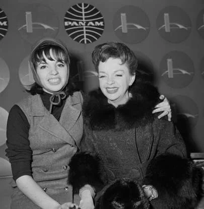 Liza Minnelli and Judy Garland seated together in a black-and-white photograph